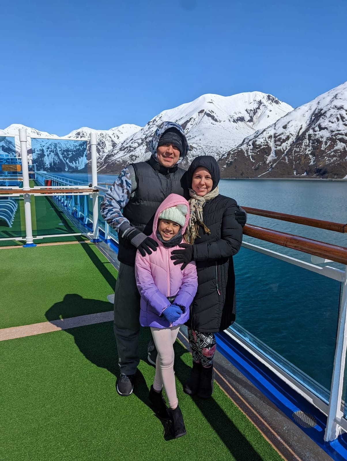 Jessica and her family on deck in front of snow-capped mountains on an Alaskan cruise